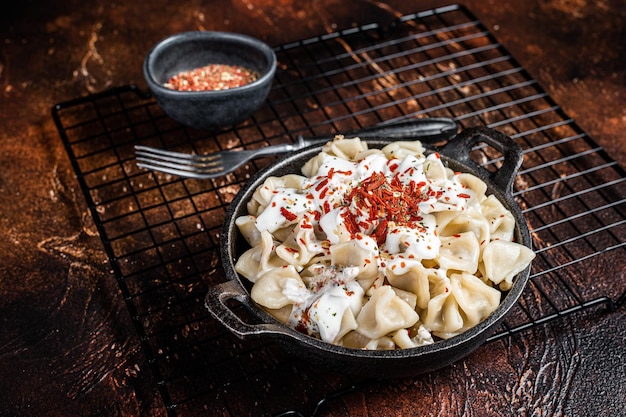 Фото Приготовление manti dumpling с йогуртом и томатным соусом в сковороде темный фон верхний вид