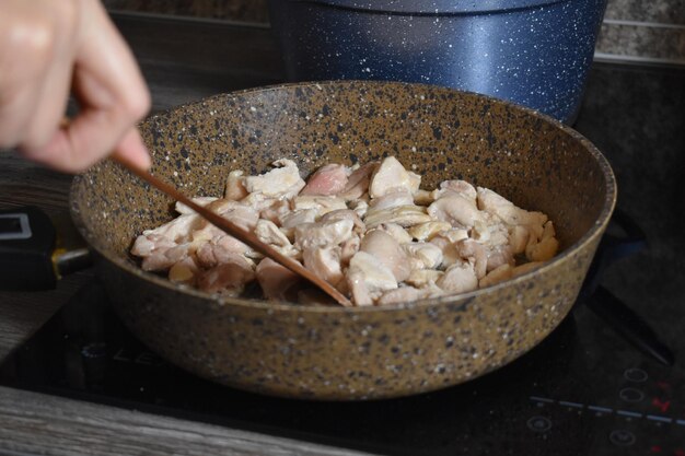キッチンのストーブの鍋で肉を調理します。肉片をフライパンで揚げる
