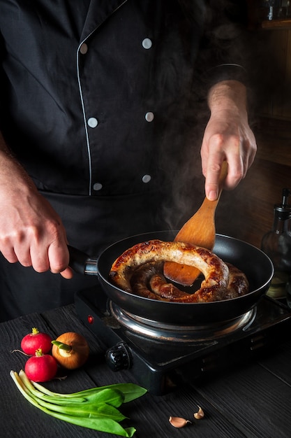 cooking meat sausage in restaurant kitchen the chef fries sausage in a frying pan