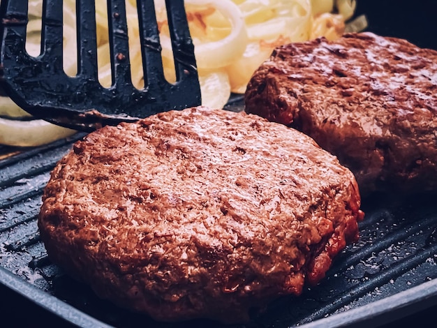 Cooking minced beef burger on cast iron grill skillet outdoors red meat on frying pan grilling food in the garden English countryside living