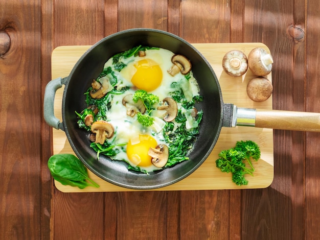 Cooking pan with spinach mushrooms cheese and fried eggs healthy homemade dish for low carb diet on