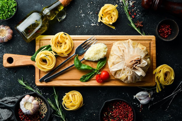 Cottura della pasta alla carbonara con uovo e parmigiano basilico su sfondo di pietra nera vista dall'alto stile rustico