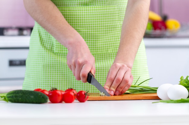 Cooking person in apron chopping eco friendly products for fresh healthy vegetables salad in the kitchen at home.