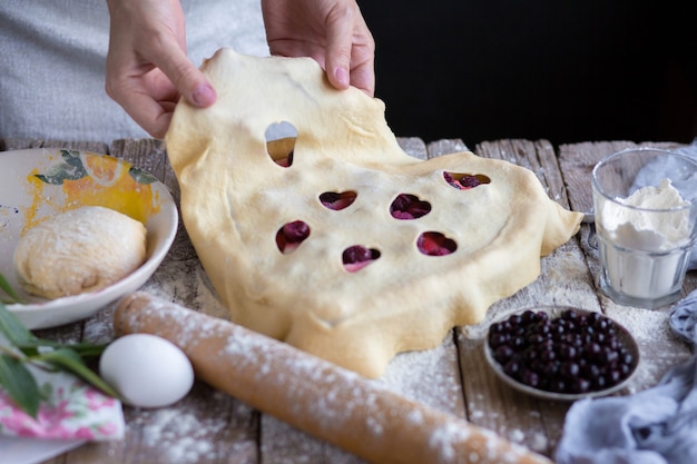 パイを調理します。手が生地をケーキの上に広げます。閉じたパイ。パイを作るプロセス。家で焼きます。ママが焼く。かみ傷の形