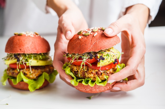 Cooking pink vegan burgers with beans cutlet, avocado and sprouts on white 