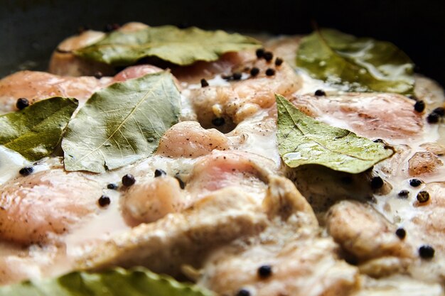 Cooking poultry meat. Pieces of raw chicken fillet with laurel leaves and pepper