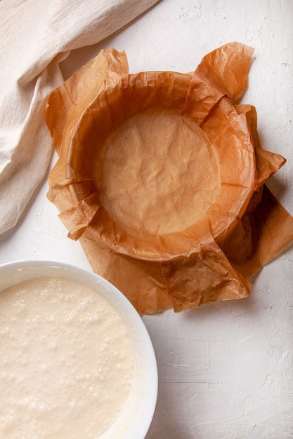 Cooking process Basque burnt cheesecake. The dough is poured into a baking dish covered with paper. Recipe step by step flat lay top view.