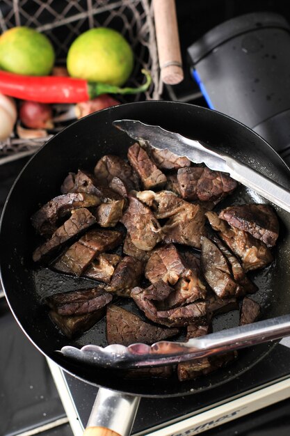 Cooking process frying beef lungs on black pan with less\
oil