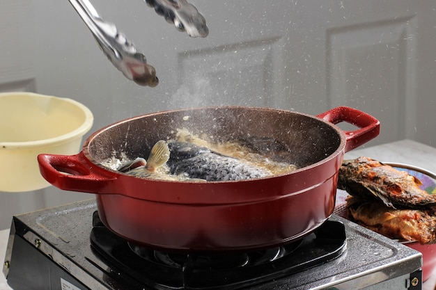 Cooking process at home oil splatter during cooking fish with\
red pan