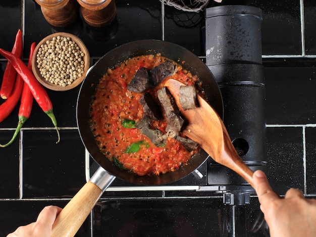 調理プロセスキッチンの鍋にサンバルまたはサンバルまたはライムの葉を添えたスパイシーソースを炒める