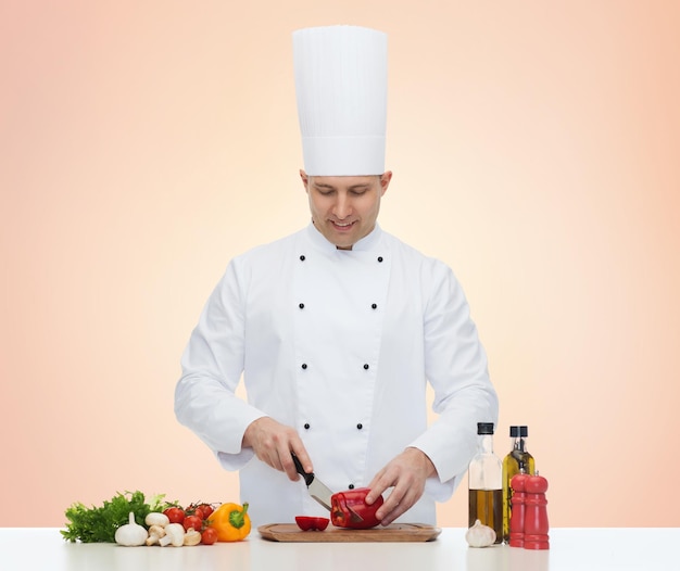 cooking, profession, vegetarian, food and people concept - happy male chef chopping pepper over beige background