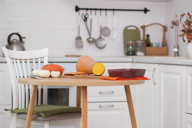 Photo cooking pumpkin for baking in ceramic dish on wooden board on wooden table in cozy kitchen