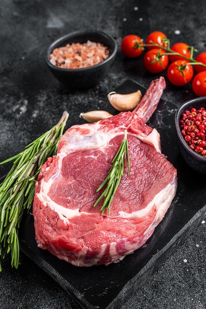 Cooking raw rib eye or tomahawk beef steak with spices black\
background top view