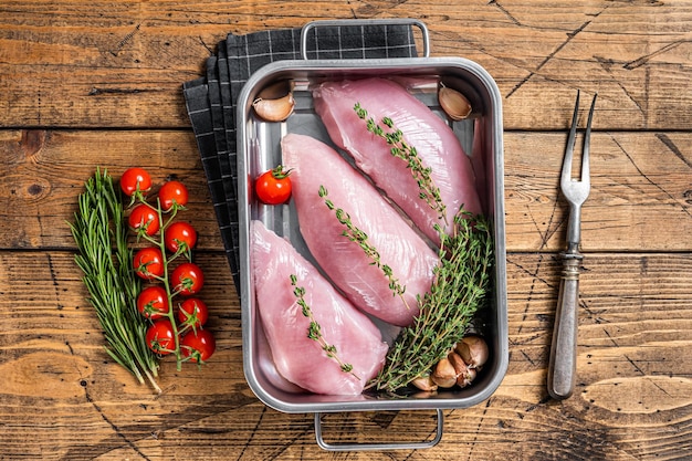 Cooking of Raw Turkey steaks Breasts fillet with thyme and rosemary Wooden background Top view