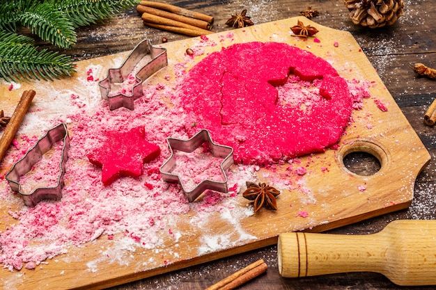 Cooking red ginger cookies. Traditional Christmas pastries. Fir tree, spices, cookie cutters, raw dough, rolling pin, wooden boards