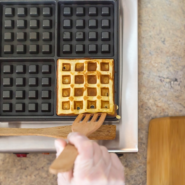 Cooking ruddy yellow Belgian waffles on a special waffle iron. 