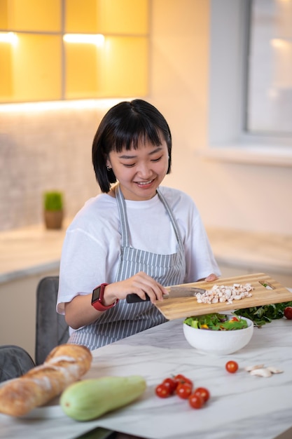 クッキングサラダ。キッチンで新鮮な野菜からサラダを作る女性