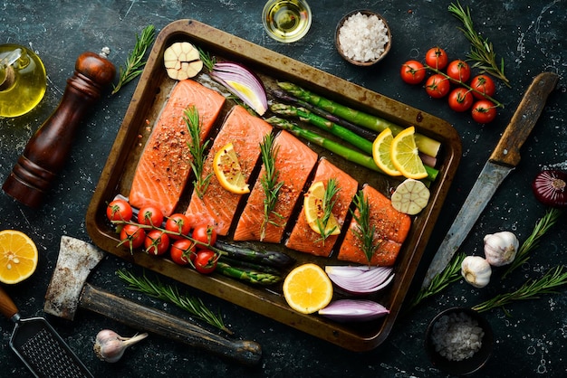Cooking salmon with asparagus lemon and vegetables in a metal baking dish Seafood Top view Free space for text