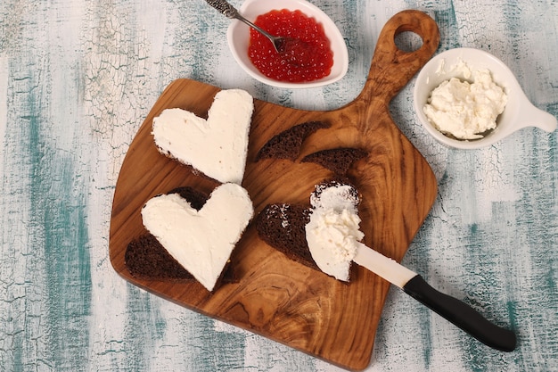 Cooking sandwiches with red caviar and cream cheese in the shape of a heart for Valentine's Day, Top view