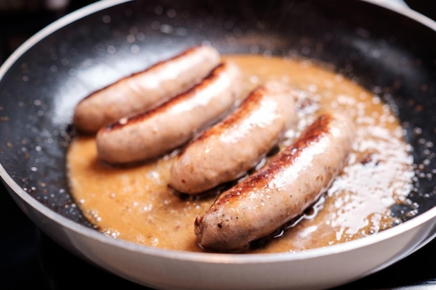 Photo cooking sausages in the dripping pan with oil