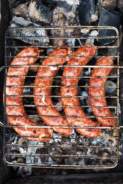 Cooking sausages on the grill in the barbecue outdoors on a picnic