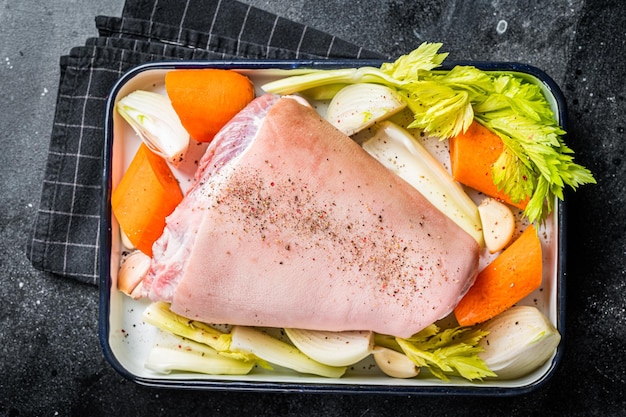 야채와 허브를 곁들인 생 돼지고기 정강이 너클에서 Schweinshaxe 요리 검은색 배경 상위 뷰