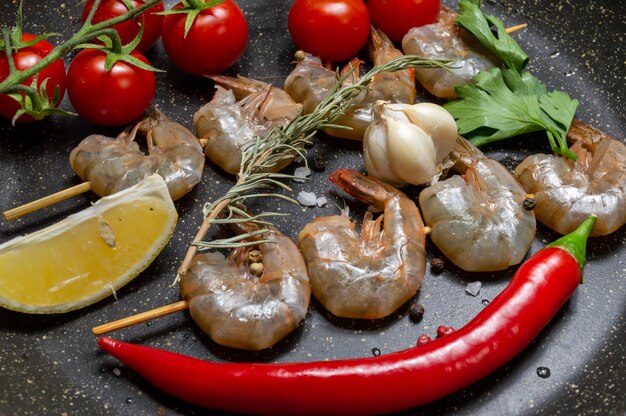 Cooking shrimp in a pan with tomatoes and hot peppers