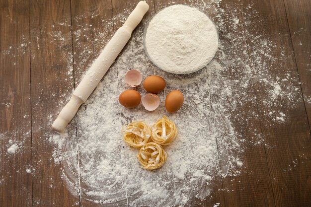 Cooking some delicious thing with chicken eggs, flour and pasta. View from above.