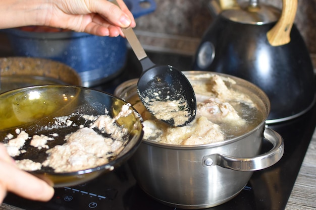 キッチンのストーブの上の鍋でスープを調理します。スープをすくい取る