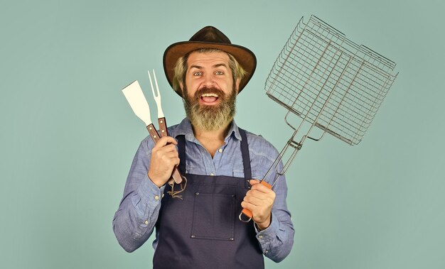 요리 스테이크 요리 도구 여름 피크닉 바베큐 미국 전통 요리 개념 학사의 날 미디엄 레어 도구 고기 구이 앞치마를 입은 남자 바비큐 그릴 바비큐 장비를 가진 농부