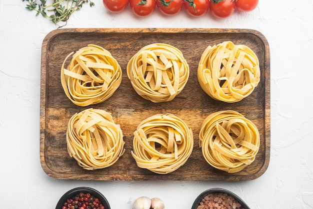 Cooking tagliatelle pasta and ingredients on white stone background top view flat lay