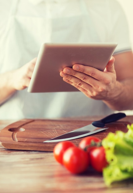 cooking, technology and home concept - closeup of man pointing finger to tablet pc computer