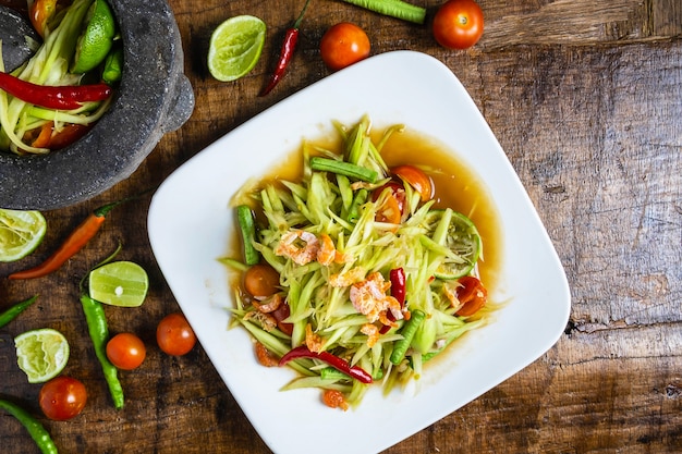 Cooking Thai food, papaya salad and papaya salad in a dish with a serving on a wooden table.