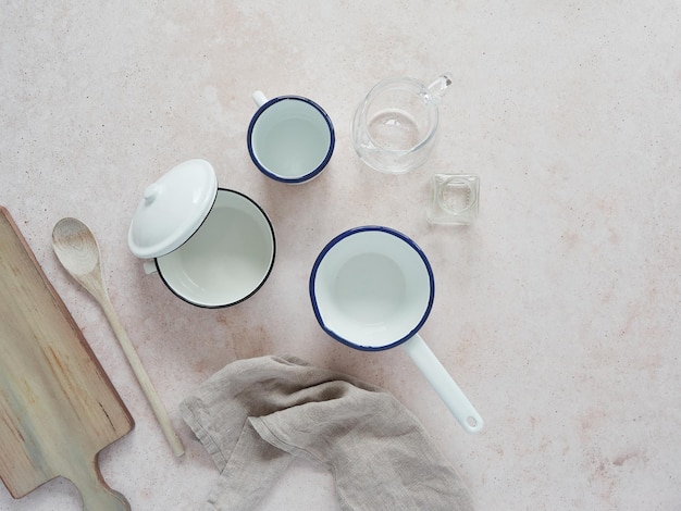 Cooking tools Empty enamel iron and glass kitchen containers beside wooden utensils on pink marbel countertop