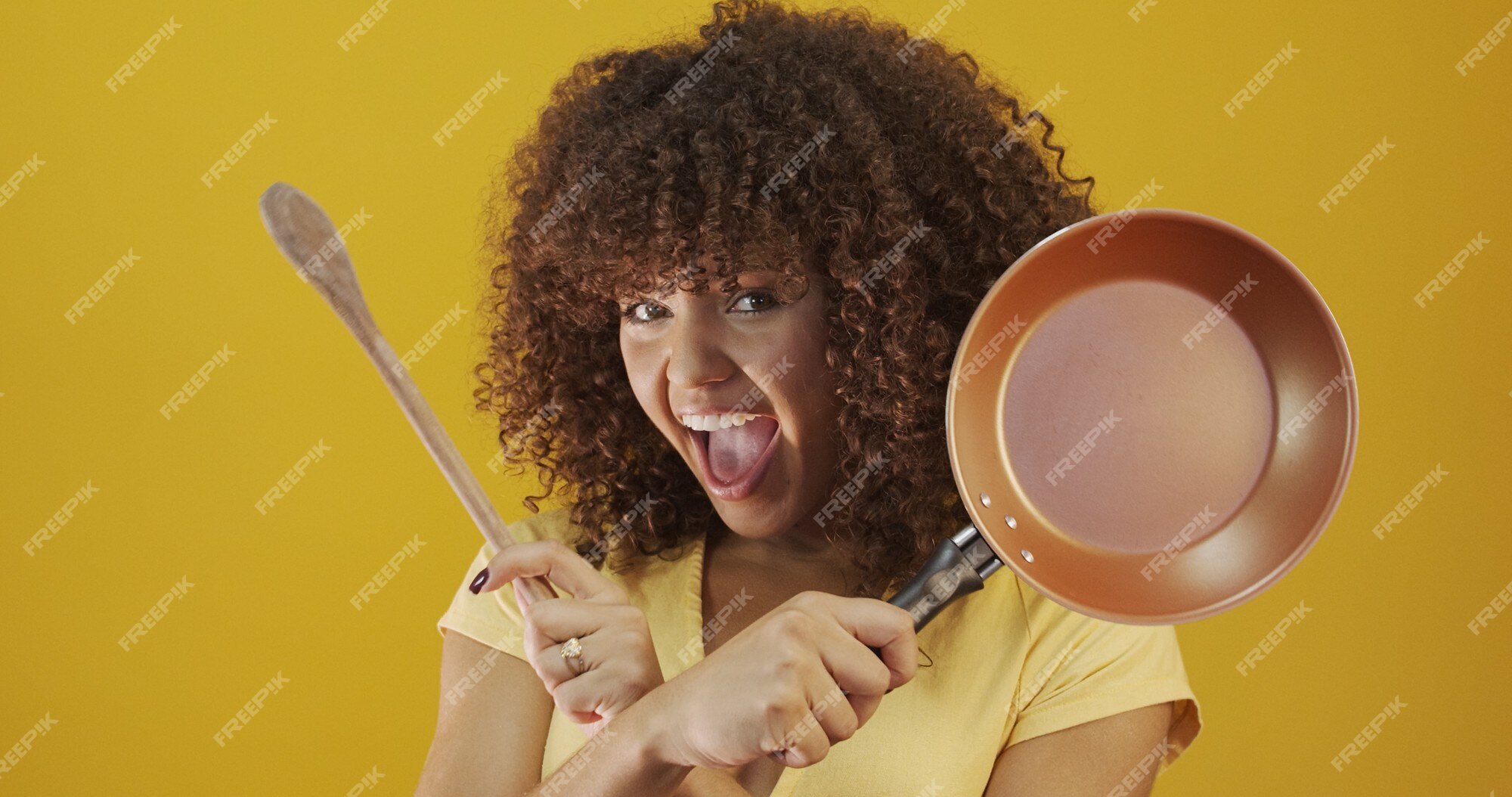 Cooking utensils. Cooking woman in kitchen with frying pan and wooden  spoon. Housewife dancing. Stock Photo