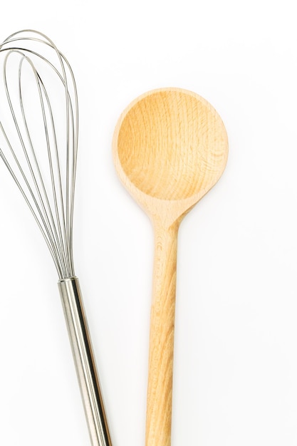 Photo a cooking whisk with wooden spoon isolated on white background. taken in studio with a 5d mark iii.