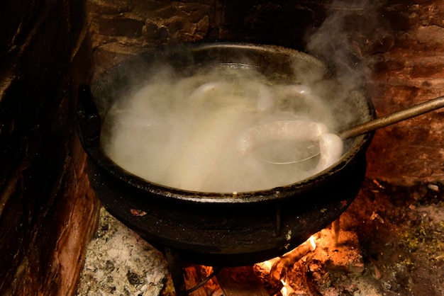 Cooking white blood sausage in an iron saucepan on a stove