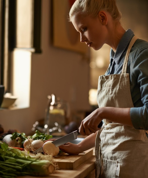 Фото Кулинарная женщина и котлет овощей с ножом в доме с диетическим питанием и здоровой едой кухня зеленая и счастливая от органического и веганского обеда с грибами и деревянной доской с благополучием