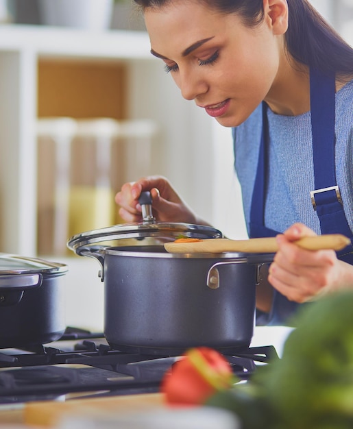 木のスプーンでキッチンで女性を料理