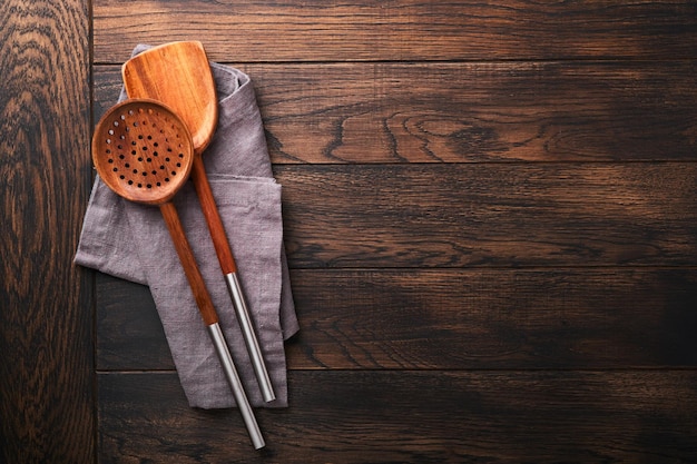 Cooking wooden utensils basil leaves and spices on old wooden background Abstract food background Top view of dark rustic kitchen table with wooden cooking spoon frame Banner for your design