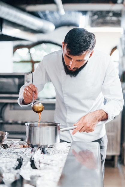 Cooks delicious soup Chef in white uniform cooking food at kitchen Busy day at work