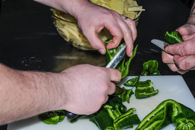 Cooks hands chopping green peppers