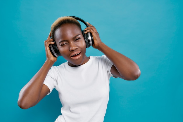 Cool african girl in white shirt listening music in studio