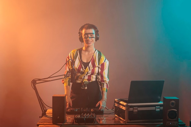 테크노 음악을 재생하기 위해 DJ 오디오 악기와 장비를 사용하여 턴테이블에서 곡을 믹싱하는 멋진 아티스트. 미친 화장을 한 행복한 여성은 전자 제품을 사용하여 음악 공연을 합니다.