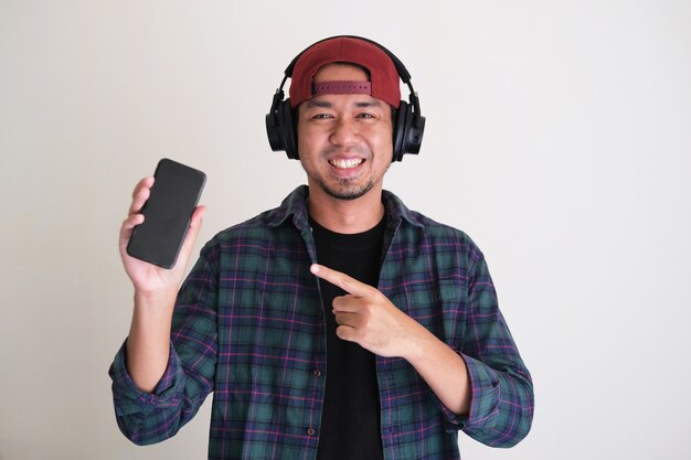 Cool asian man smiling and pointing finger to his mobile phone