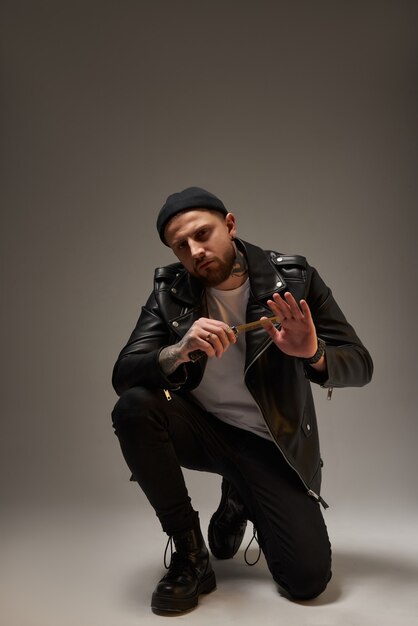 Cool bearded tattooed man in leather jacket in studio