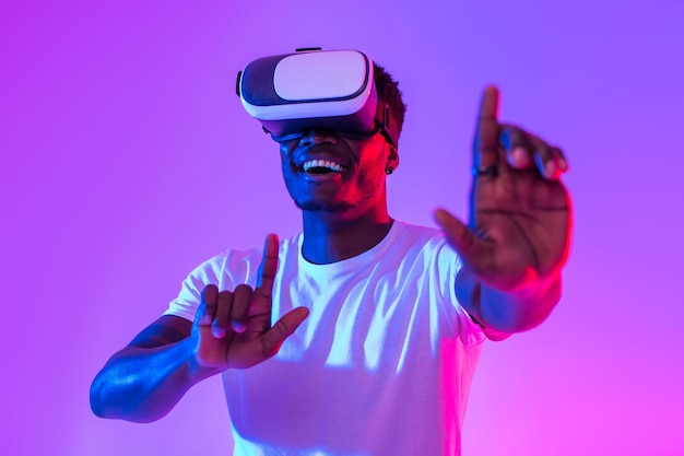 Cool black guy in vr glasses exploring cyberspace touching imaginary screen playing virtual reality