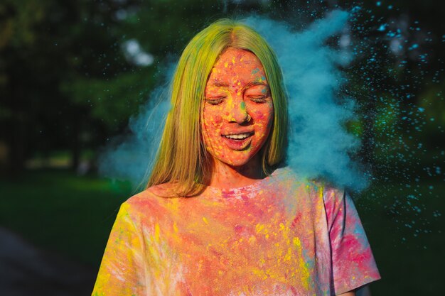 Cool blonde vrouw speelt met exploderend droog kleurrijk poeder op het Holi Festival