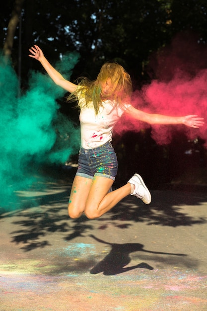 Cool blonde woman jumping with vibrant colors exploding around her