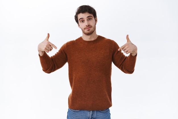 Cool and confident handsome bearded man pointing fingers down